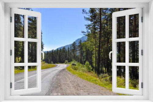 Fototapeta Naklejka Na Ścianę Okno 3D - A beautiful mountain landscape with an asphalt road in the middle of a dense forest. The road winds and has many dangerous and sharp turns.