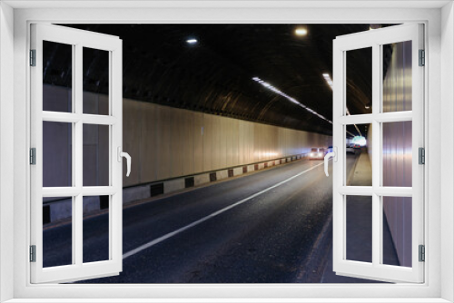 Road tunnel in mountain illuminated by lamps