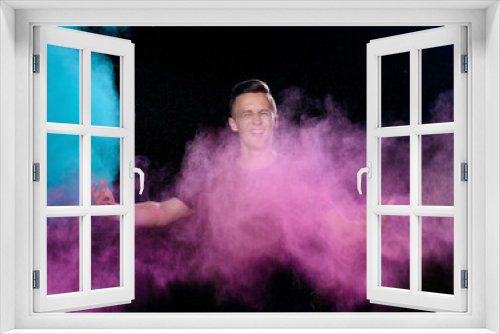 Fototapeta Naklejka Na Ścianę Okno 3D - A young caucasian emotionally guy is standing strewn with holi paints on a dark background