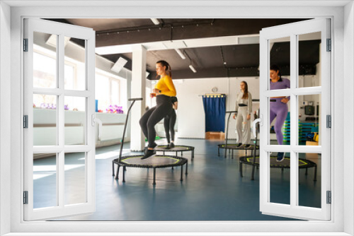 Four young women on trampoline, young fitness girls trains on   fitness studio.