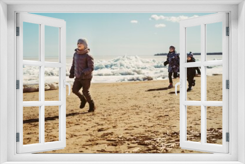 Fototapeta Naklejka Na Ścianę Okno 3D - boys running along beach of finland gulf covered with ice. Image with selective focus