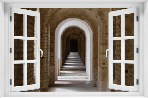 Fototapeta Naklejka Na Ścianę Okno 3D - Arched brick corridor with shadows and daylight through the windows in the old fortress in Komárno, a place full of history, Slovakia