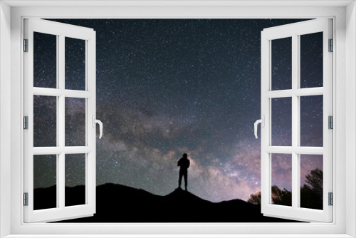 Fototapeta Naklejka Na Ścianę Okno 3D - Silhouette traveler on the hill in starry night sky.  Bright milky way galaxy behind him. 