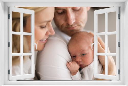 Smiling mother and father holding their newborn baby daughter at home