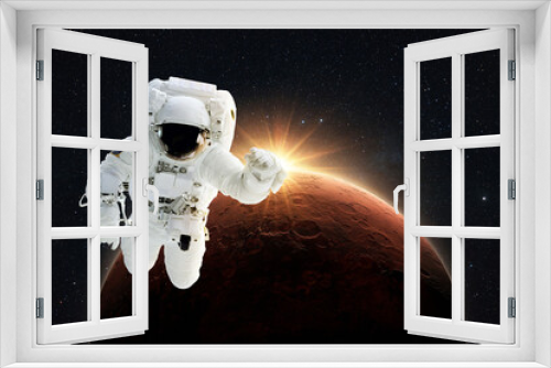 Fototapeta Naklejka Na Ścianę Okno 3D - New spaceman flies in gravity in outer space on a backgrounds of the amazing red planet Mars with orange dawn rays in space. Astronaut Journey to the Planet Mars Concept
