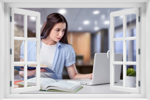 Business And Education Concept. Smiling young woman sitting at desk working on laptop