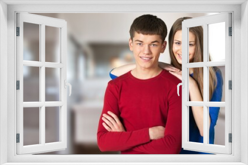Portrait of cheerful couple welcoming inviting guests to enter home, happy young guy and lady hugging