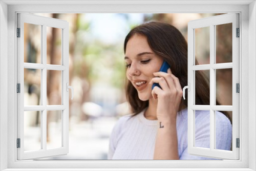 Young woman smiling confident talking on the smartphone at street