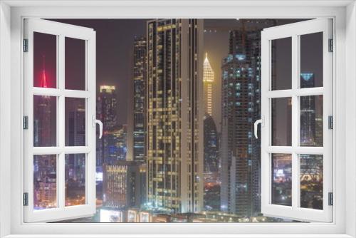 Fototapeta Naklejka Na Ścianę Okno 3D - Row of the tall buildings around Sheikh Zayed Road and DIFC district aerial night timelapse in Dubai