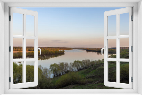 Fototapeta Naklejka Na Ścianę Okno 3D - Evening landscape. Cloudy May day. Clouds are reflected in the lake. Peaceful landscape on the banks of the reservoir. Relax in nature.