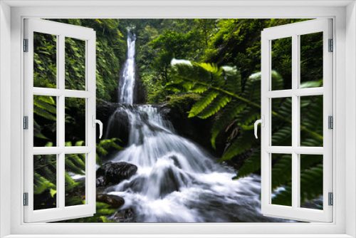 Fototapeta Naklejka Na Ścianę Okno 3D - Long exposure shot of tropic waterfall framed by leafs