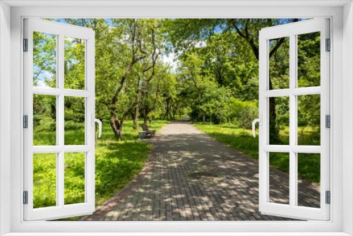 Fototapeta Naklejka Na Ścianę Okno 3D - Landscaping of a parking area with flowers and trees on a sunny day, an ennobled park area in a botanical garden with paths and green trees