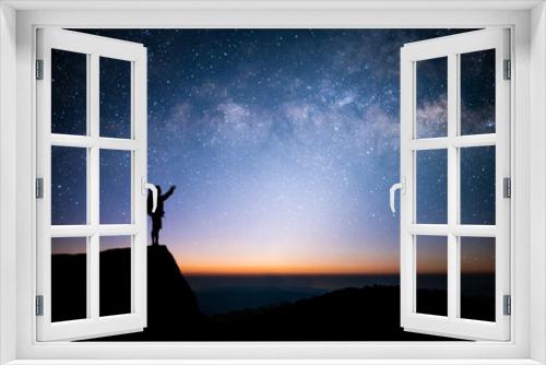 Fototapeta Naklejka Na Ścianę Okno 3D - Silhouette of young man standing and watched the star, milky way and night sky alone on top of the mountain. He enjoyed traveling and was successful when he reached the summit.