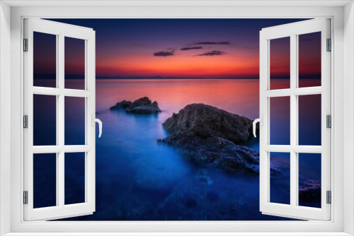 Fototapeta Naklejka Na Ścianę Okno 3D - Widok skał oblewanych przez morze o wschodzie słońca przy kolorowym niebie