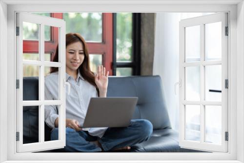 Happy young woman using laptop at home sitting on soft couch. Lady is working on laptop computer. Girl student is typing message using laptop keyboard.