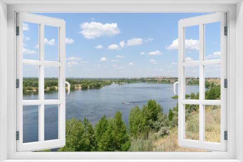 Fototapeta Naklejka Na Ścianę Okno 3D - Summer landscape with a river and blue sky during the day. The boat floats on the river.