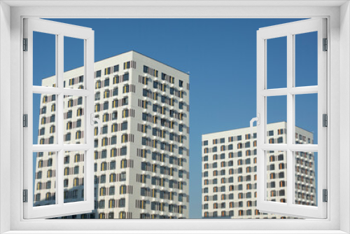 Fototapeta Naklejka Na Ścianę Okno 3D - Two white buildings against blue sky. Two modern houses. View of city.