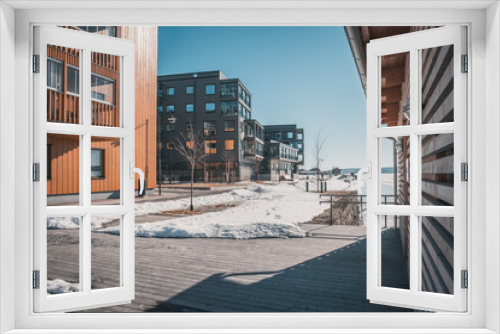 Fototapeta Naklejka Na Ścianę Okno 3D - March in Östersund, Sweden - Wooden buildings of new city quarter called Storsjö Strand during spring winter under blue sky on the waterfront to Lake Storsjön.