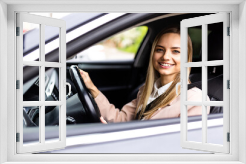 Young woman driving a car in the city. Portrait of a beautiful woman in a car, looking out of the window and smiling. Travel and vacations concepts