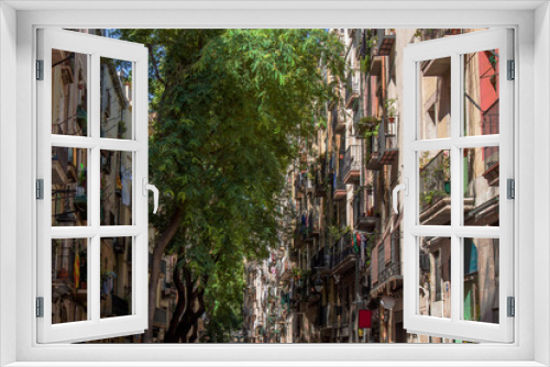 Fototapeta Naklejka Na Ścianę Okno 3D - Crowded narrow streets with colorful historical buildings in the old town of Barcelona, Catalonia, Spain, Europe. Trees and typical Mediterranean houses in the gothic quarter of the Catalan Capital.