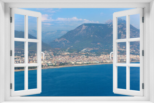 Fototapeta Naklejka Na Ścianę Okno 3D - Panoramic view of the coast of Alanya, Turkey. Residential houses, hotels against the backdrop of mountains. Blue water and golden beaches in sunlight. Aerial view