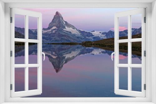 Fototapeta Naklejka Na Ścianę Okno 3D - Early lights of dawn on Matterhorn summit reflecting on a mountain lake.