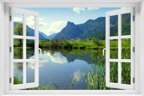 Fototapeta Naklejka Na Ścianę Okno 3D - kleiner Teich eines Biotops im Ammergau mit Wald.,  Schilf,  Wiesen und Bergen unter blauem Himmel