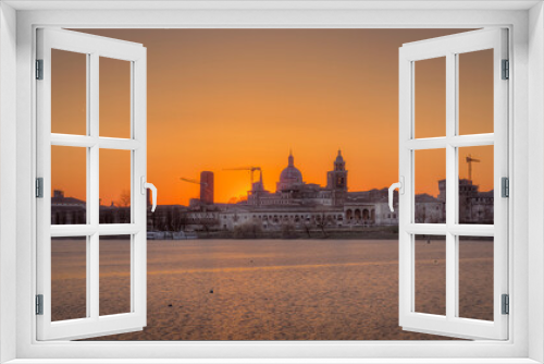 Fototapeta Naklejka Na Ścianę Okno 3D - View of Mantua historic center from the upper lake. Sunset February 2022, visible the basilica, the Gonzaga castle and the bridge that connects the city on the north side. You can see the many medieva