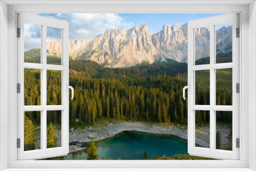 Fototapeta Naklejka Na Ścianę Okno 3D - Stunning view of Carezza Lake (Lago di Carezza) with its emerald green waters, beautiful trees and mountains in the distance during a dramatic sunset.