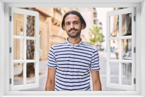 Young hispanic man with beard outdoors at the city relaxed with serious expression on face. simple and natural looking at the camera.