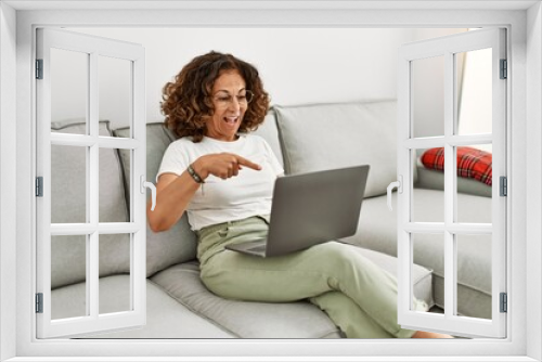 Middle age hispanic woman working using computer laptop at home smiling happy pointing with hand and finger