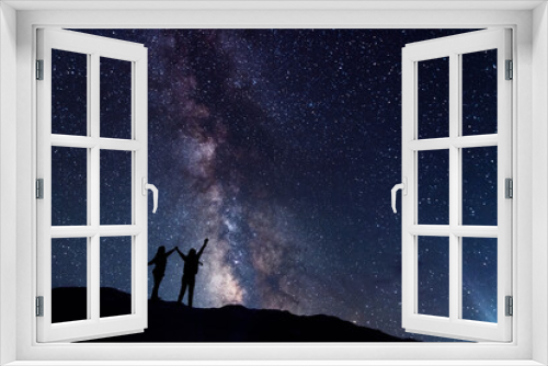 Fototapeta Naklejka Na Ścianę Okno 3D - Two hiker silhouette stands on the hill and looking at the bright milky way galaxy in the starry night.
