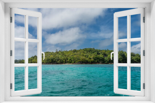 Fototapeta Naklejka Na Ścianę Okno 3D - A tropical island in the ocean is completely covered with lush green vegetation. Aquamarine water and blue sky with clouds. Seychelles