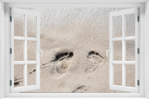 Fototapeta Naklejka Na Ścianę Okno 3D - Traces of children's feet in the wet sand at the beach. Sandy beach with footprints. Beach holiday.