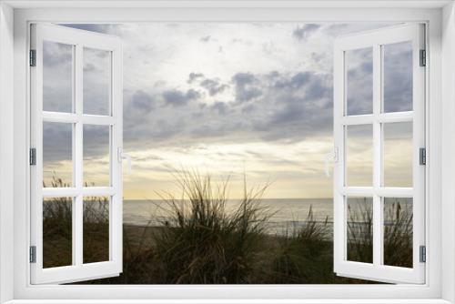 Fototapeta Naklejka Na Ścianę Okno 3D - Dünengras mit Blick auf das Meer und dramatischen Sonnenuntergang mit dunklen Wolken 