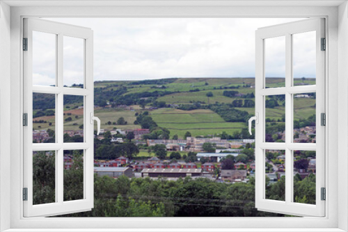 Fototapeta Naklejka Na Ścianę Okno 3D - a long panoramic view of the town of mytholmroyd from above with buildings and streets of the town visible in the valley with surrounding pennine hills and fields