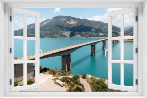 Fototapeta Naklejka Na Ścianę Okno 3D - Drone view of bridge over blue lake with mountains at background. Central Greece