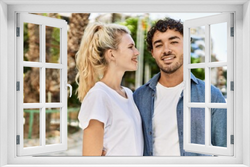 Young beautiful couple of caucasian girlfriend and hispanic boyfriend hugging in love outdoors on a sunny day. Woman and man smiling happy dating relationship