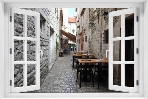 Fototapeta Naklejka Na Ścianę Okno 3D - Tiny restaurant in secluded narrow back alley in Trogir, Croatia. Empty tables with flowers and menus. No people.