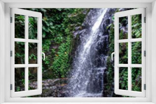 Fototapeta Naklejka Na Ścianę Okno 3D - A waterfall in the middle of a forest with a stone wall around it