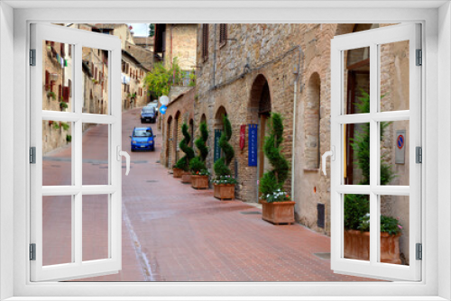 Fototapeta Naklejka Na Ścianę Okno 3D - Italy, Tuscany, San Gimignano. Homes decorated with flower pots along the streets of San Gimignano.