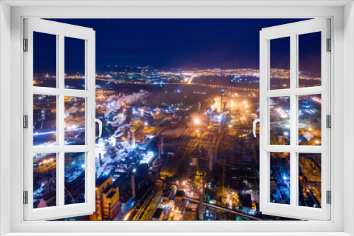 Fototapeta Naklejka Na Ścianę Okno 3D - Aerial view of steel plant at night with smokestacks and fire blazing out of the pipe. Industrial panoramic landmark with blast furnance of metallurgical production. Concept of environmental pollution