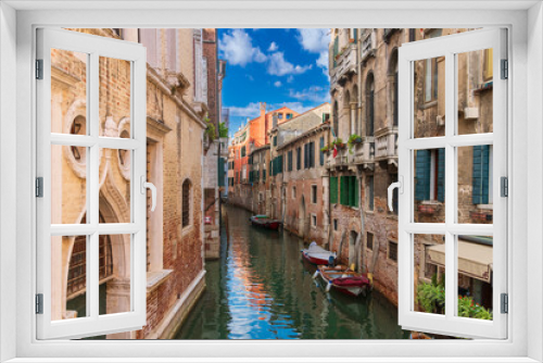Fototapeta Naklejka Na Ścianę Okno 3D - Boats near a vintage brick wall on the water surface of a narrow canal street in Venice, reflections of old houses with windows on a Venetian street, Venice canal on a sunny day