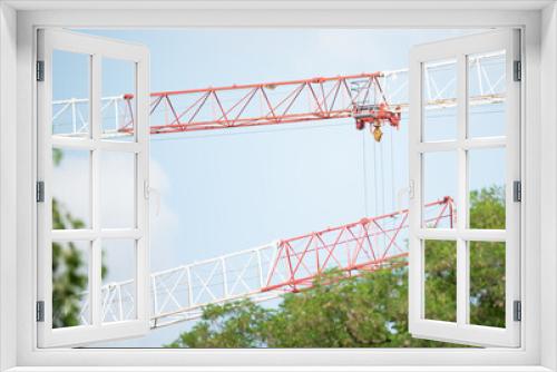 Fototapeta Naklejka Na Ścianę Okno 3D - Construction crane between the treetops. Construction crane structure and cabin.