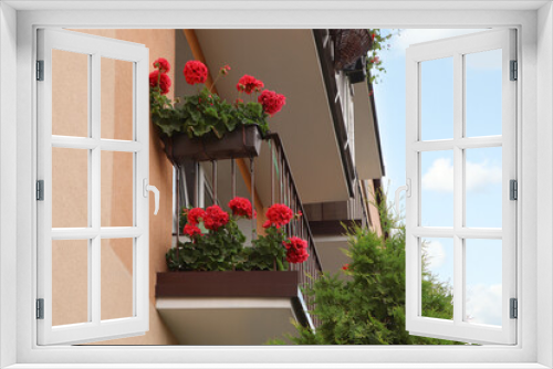 Fototapeta Naklejka Na Ścianę Okno 3D - Balcony decorated with beautiful red flowers, low angle view