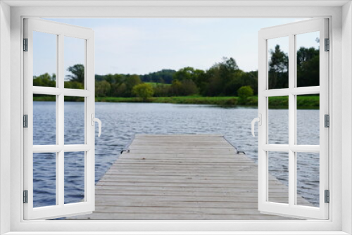 Fototapeta Naklejka Na Ścianę Okno 3D - A short boat dock sits on a lake.
