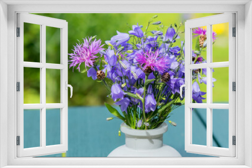 Fototapeta Naklejka Na Ścianę Okno 3D - Fresh beautiful summer bouquet of blue field bells with cornflowers in a vase on a garden table.