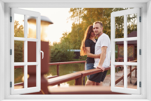 Happy wife and husband is outdoors on the wooden bridge at sunny day