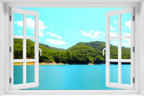 Fototapeta Naklejka Na Ścianę Okno 3D - Heavenly view at Gerosa Lake with a cyan sky and some white fluffy clouds suspended above a bulky mass of green vegetation sitting on rough hills and some clear azure waters further below