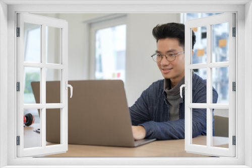 Stylish man freelancer using laptop computer in bright modern office.